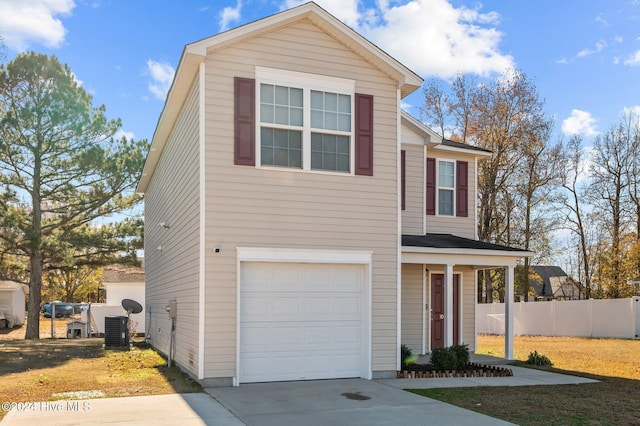 view of property featuring a front yard, central AC unit, and a garage