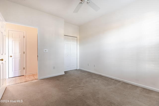 unfurnished bedroom with ceiling fan, light colored carpet, and a closet