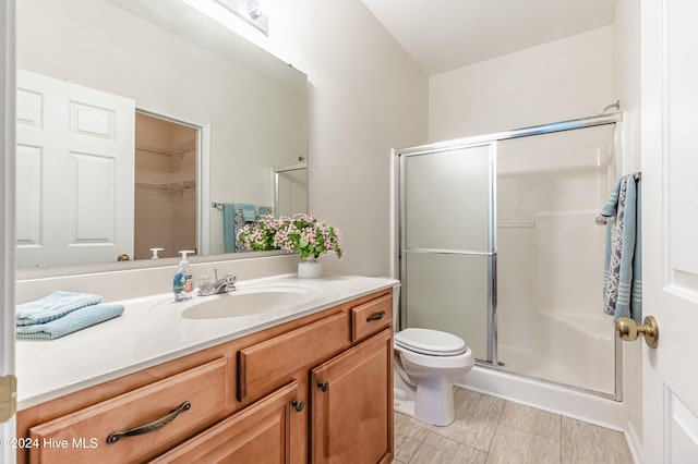 bathroom featuring tile patterned floors, vanity, toilet, and an enclosed shower