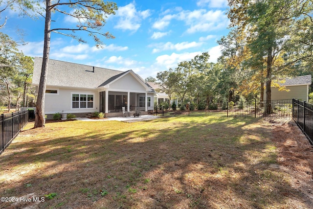 rear view of house with a lawn, a patio area, and a sunroom