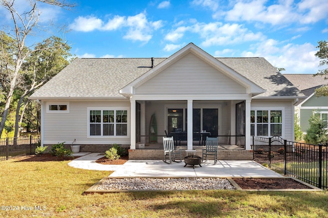 back of property featuring a patio area, a sunroom, a yard, and an outdoor fire pit