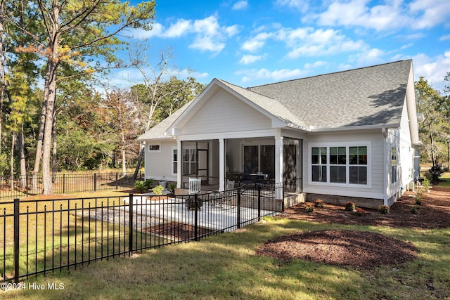 rear view of property featuring a patio area, a sunroom, and a yard