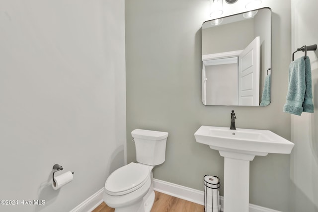 bathroom with wood-type flooring, toilet, and sink