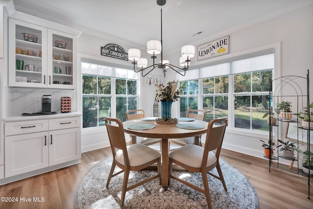 dining area featuring crown molding, light hardwood / wood-style flooring, and a notable chandelier