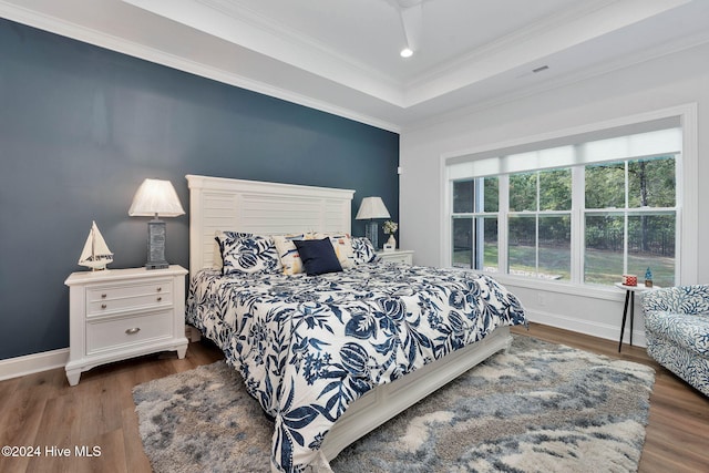 bedroom with ornamental molding, dark wood-type flooring, and a tray ceiling