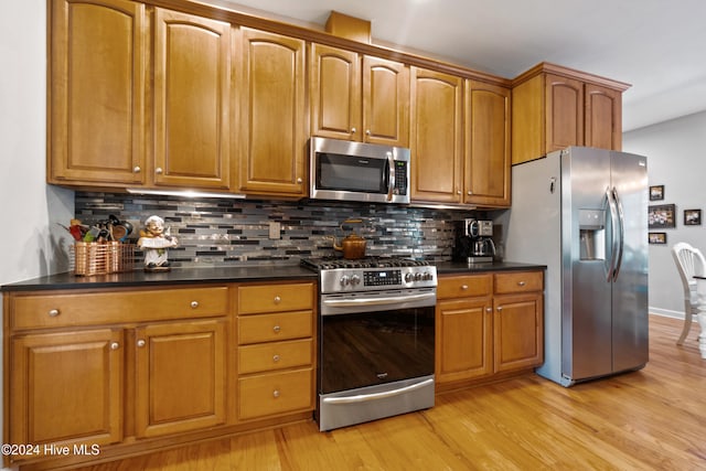 kitchen featuring light wood-type flooring, stainless steel appliances, and backsplash