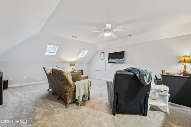 interior space featuring ceiling fan, vaulted ceiling with skylight, and light colored carpet