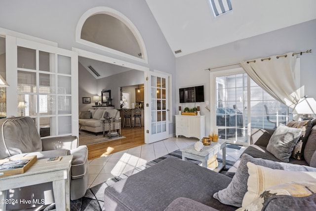 living room with french doors, light wood-type flooring, and high vaulted ceiling