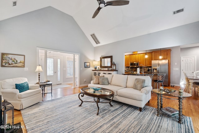 living room with ceiling fan, high vaulted ceiling, and light wood-type flooring