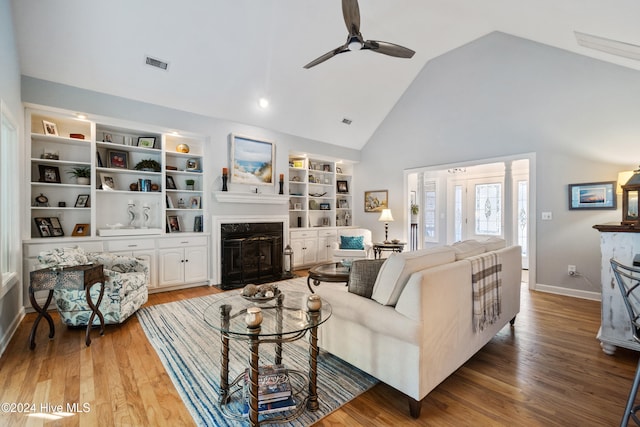 living room with a high end fireplace, wood-type flooring, high vaulted ceiling, and ceiling fan