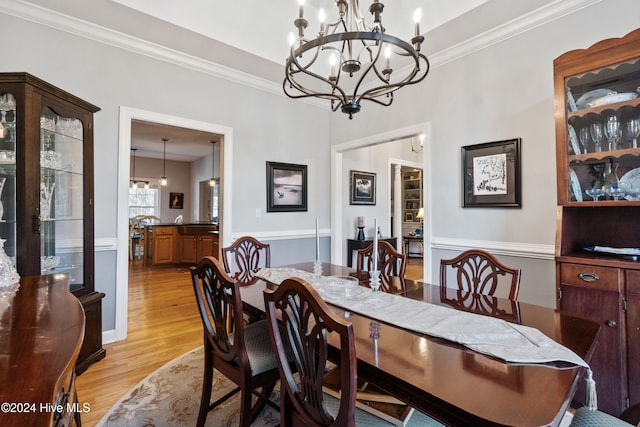 dining area featuring crown molding, light hardwood / wood-style flooring, and an inviting chandelier