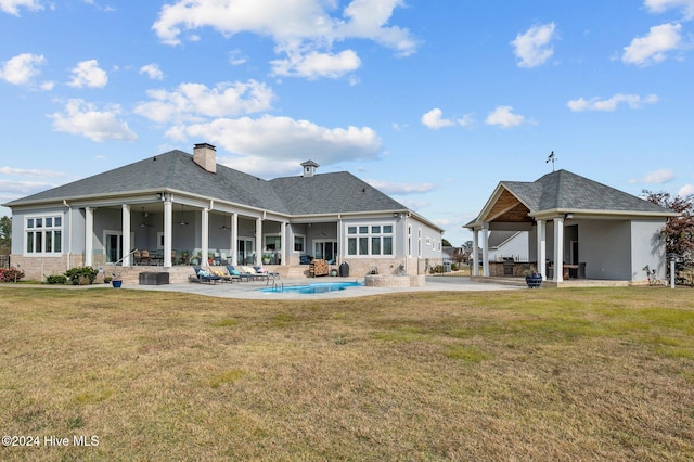 back of house featuring a lawn, a patio area, ceiling fan, and a fireplace