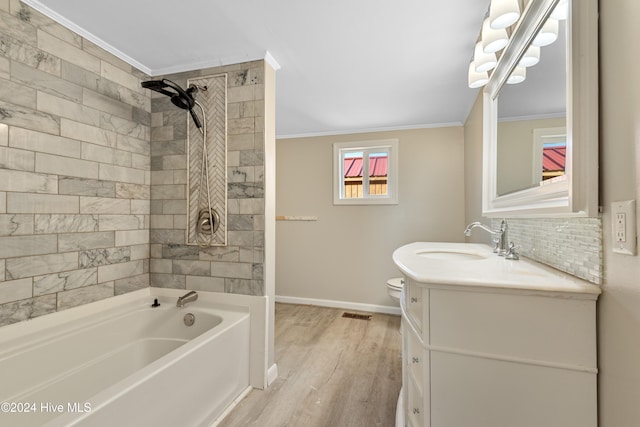 full bathroom with crown molding, wood-type flooring, toilet, vanity, and tiled shower / bath