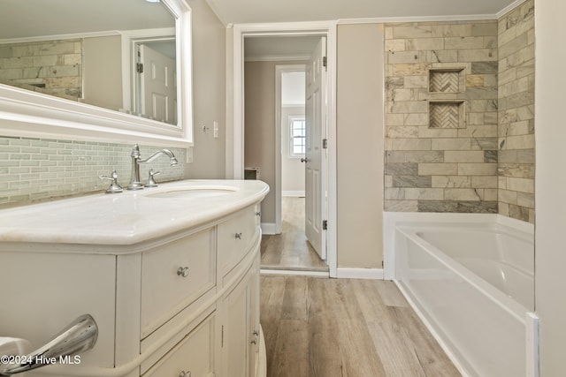 bathroom featuring vanity, hardwood / wood-style flooring, a tub, and ornamental molding