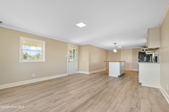 unfurnished living room featuring sink, light wood-type flooring, and ornamental molding