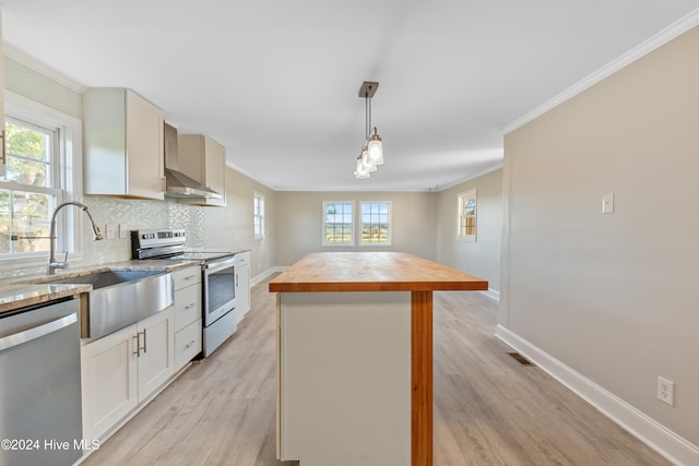 kitchen featuring a healthy amount of sunlight, a center island, wall chimney exhaust hood, and stainless steel appliances