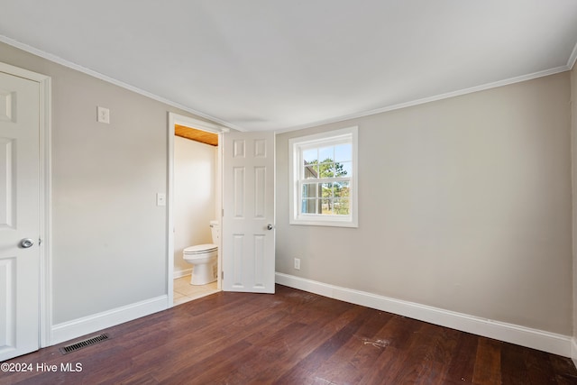 unfurnished bedroom with dark hardwood / wood-style floors, ornamental molding, and ensuite bathroom