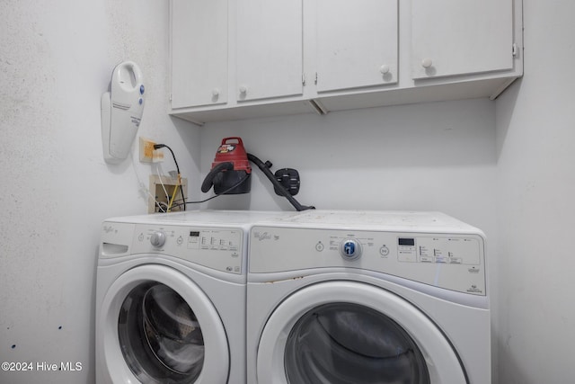 clothes washing area with separate washer and dryer and cabinets