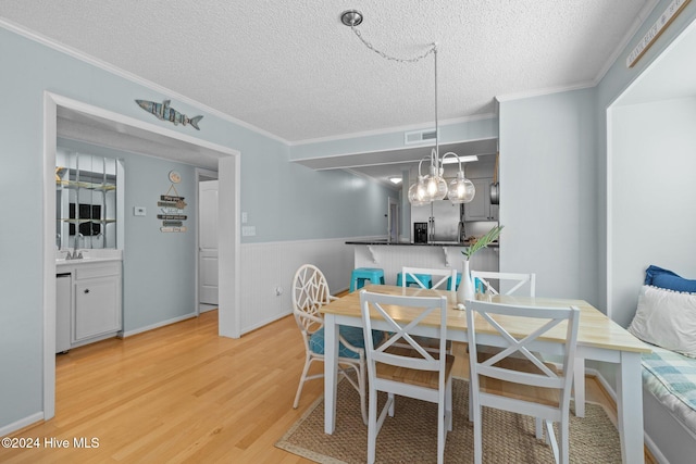 dining room with crown molding, a textured ceiling, and hardwood / wood-style flooring