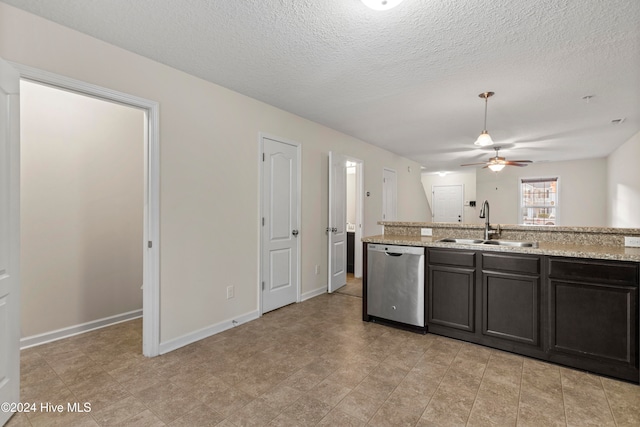 kitchen featuring light stone countertops, sink, stainless steel dishwasher, and a textured ceiling