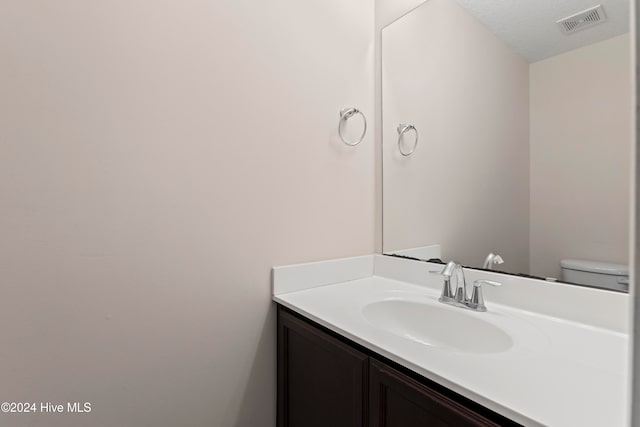 bathroom featuring vanity, toilet, and a textured ceiling