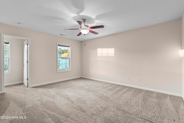 empty room featuring light carpet, a textured ceiling, and ceiling fan