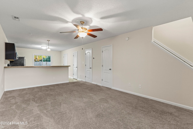 unfurnished living room with carpet, ceiling fan, and a textured ceiling