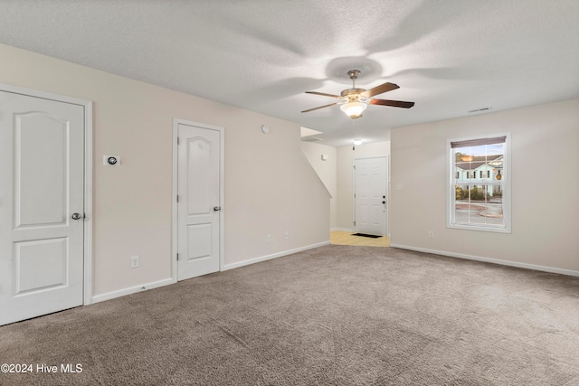 carpeted empty room with ceiling fan and a textured ceiling