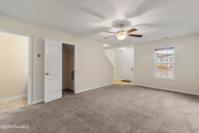 spare room with ceiling fan, light colored carpet, and a textured ceiling