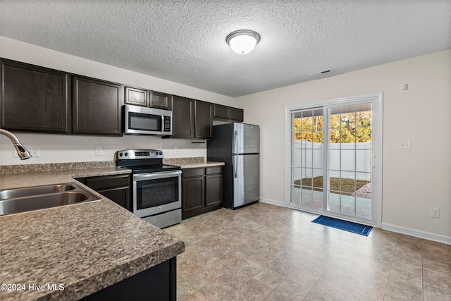 kitchen featuring a textured ceiling, sink, dark brown cabinetry, and stainless steel appliances