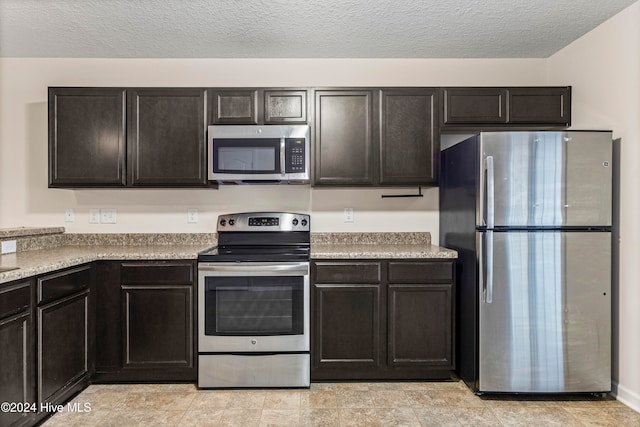 kitchen with dark brown cabinetry, stainless steel appliances, and a textured ceiling