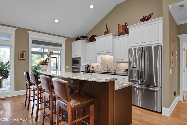 kitchen featuring white cabinetry, a center island, light hardwood / wood-style floors, lofted ceiling, and appliances with stainless steel finishes