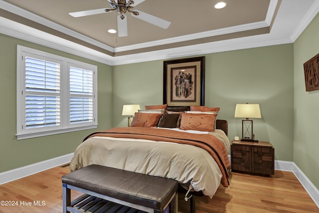 bedroom with a raised ceiling, light hardwood / wood-style flooring, ceiling fan, and ornamental molding