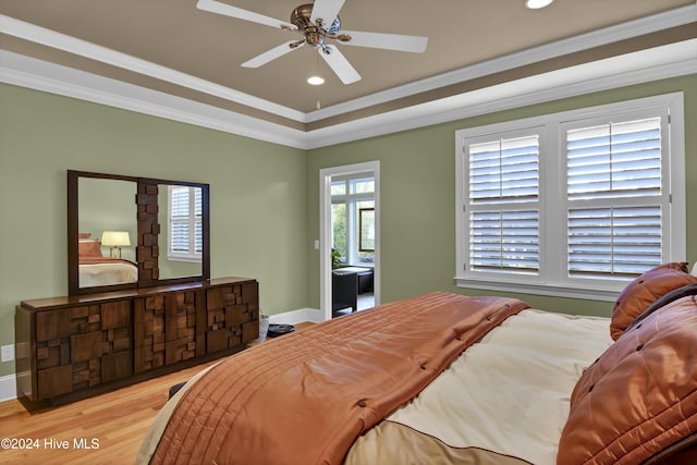 bedroom featuring light hardwood / wood-style floors, a raised ceiling, ceiling fan, and ornamental molding