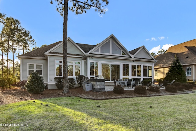 rear view of house with a lawn, a sunroom, and a patio