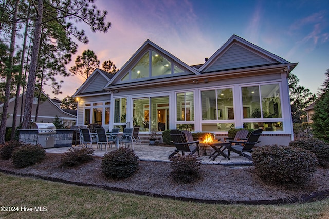 back house at dusk with a fire pit and a patio area