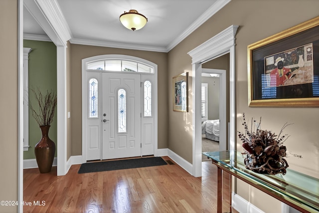 foyer entrance with light hardwood / wood-style floors and crown molding