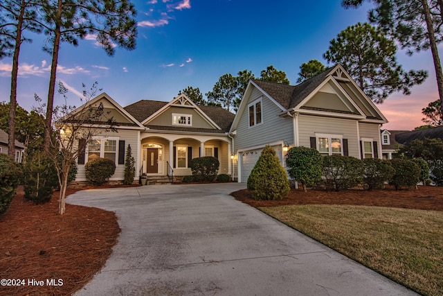 view of front of house with a yard, a porch, and a garage