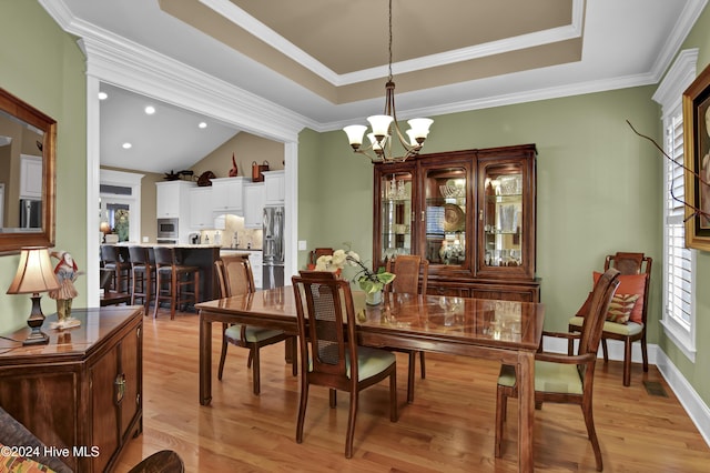 dining room with lofted ceiling, crown molding, a notable chandelier, and light wood-type flooring