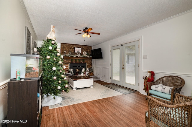 living room featuring ceiling fan, french doors, crown molding, a textured ceiling, and hardwood / wood-style flooring