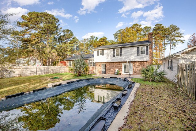 back of property featuring a yard and a covered pool