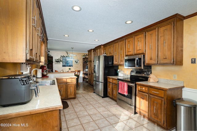 kitchen with sink, kitchen peninsula, pendant lighting, light tile patterned flooring, and appliances with stainless steel finishes