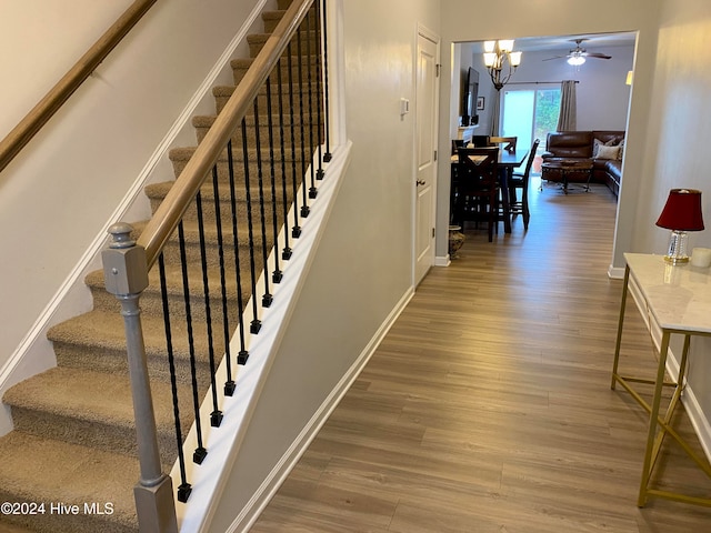 staircase with hardwood / wood-style flooring and a chandelier