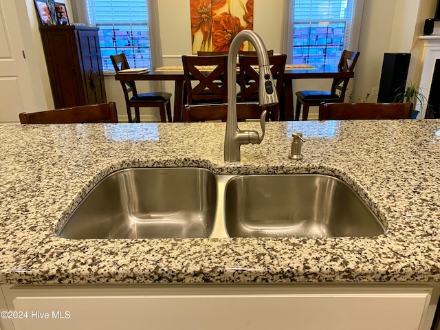 room details with light stone countertops, a kitchen bar, and sink