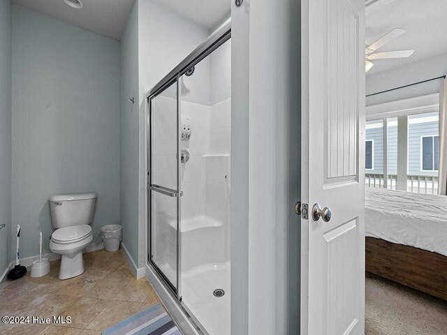 bathroom featuring tile patterned floors, toilet, ceiling fan, and a shower with shower door