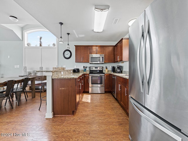 kitchen featuring pendant lighting, a breakfast bar, dark hardwood / wood-style floors, and appliances with stainless steel finishes