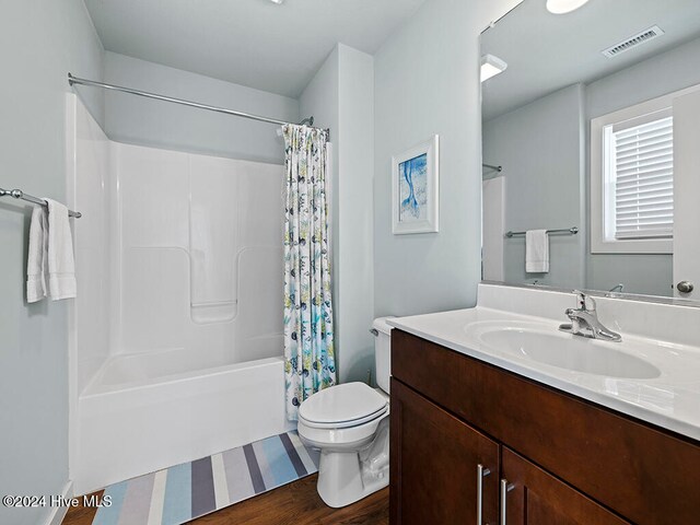 full bathroom featuring hardwood / wood-style floors, shower / bath combination with curtain, toilet, and vanity