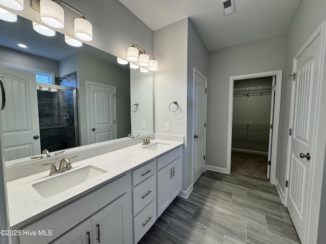 bathroom featuring a stall shower, visible vents, a sink, and double vanity