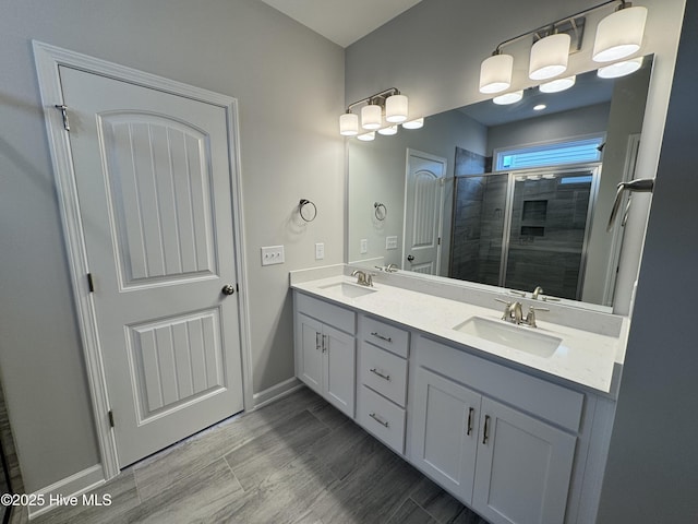 bathroom featuring double vanity, baseboards, a tile shower, and a sink