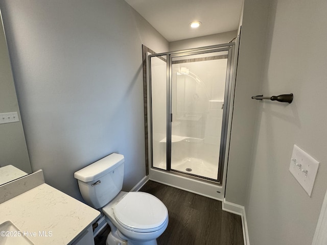 bathroom featuring toilet, wood finished floors, vanity, a stall shower, and baseboards